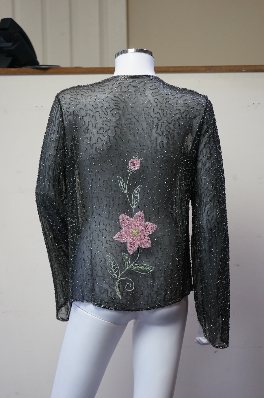 A 1930’s, multi coloured floral hand beaded evening jacket, the beading worked on black georgette. Possibly French, label on the inside of the neck 48. 64cm long. Condition - beading and georgette appear in good conditio